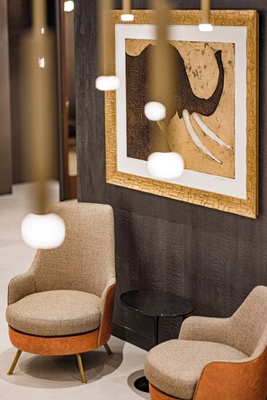 Un intérieur moderne avec deux fauteuils, une œuvre d’art encadrée et une petite table ronde.
