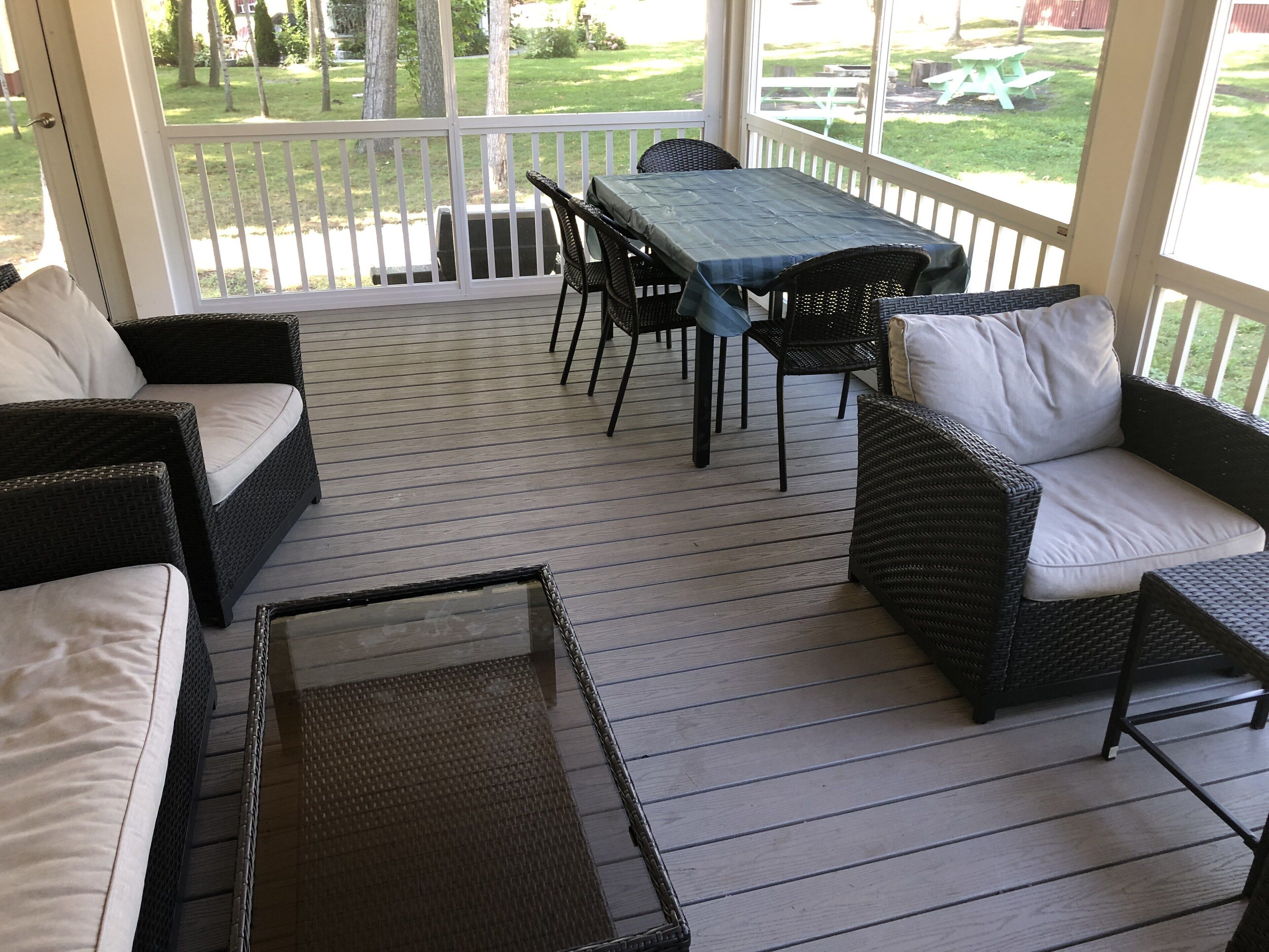 Un patio cubierto con mobiliario de mimbre, una mesa y sillas.