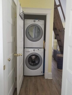 Un cuarto de lavandería con dos lavadoras de carga frontal apiladas.