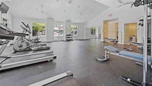 Un gimnasio amplio con máquinas de cardio, equipo de levantamiento de pesas y bancos.
