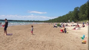 Una playa con gente, tiendas de campaña y equipo de playa.