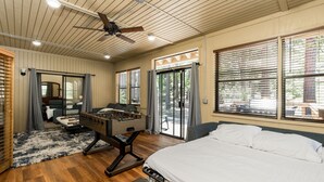 A spacious room with a large bed, a foosball table, and a ceiling fan.