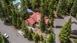 An aerial view of a residential area with multiple houses, surrounded by dense trees.
