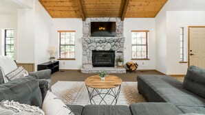 A living room with a stone fireplace, wooden ceiling, and a large sofa.