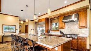 A spacious kitchen with a large island, stainless steel appliances, wooden cabinets, and pendant lighting. - 🏖️  GORGEOUS Hawaii Home | Private Pool & AC | Concierge Included | Resort Access! (Kamuela)
