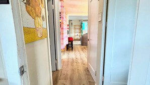 A hallway with wooden flooring, white walls, and a ceiling light fixture.