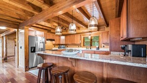 A spacious kitchen with wooden cabinets, a granite countertop, and hanging pendant lights.