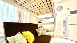 A modern room with a brown sofa, a white table, and a ceiling with wooden beams. - Le Soleil Asato (Naha)