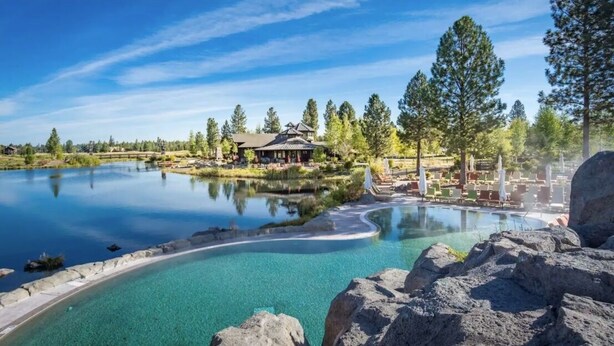 Ein Resort mit einem klaren Pool, einer Lodge und einer Lounge-Bereich mit Sonnenschirmen.
