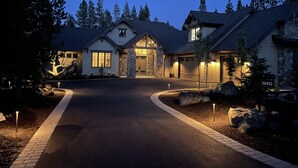 Ein zweistöckiges Haus mit Naturstein-Fassade, einer Garage und einer Auffahrt zum Eingang.