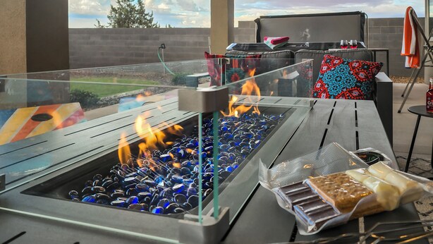 An outdoor grill with a glass enclosure, a barbecue table, and a view of the sky.