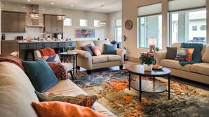 A modern living room with a sofa, two armchairs, a coffee table, and a rug.