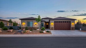 A modern two-story house with a garage, landscaped garden, and exterior lighting.