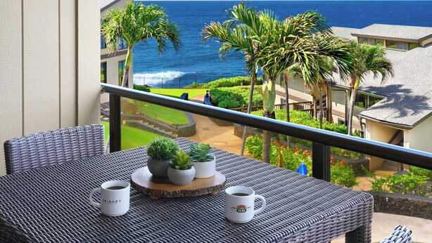 A balcony with wicker furniture, two coffee mugs, and potted plants. - Expansive Views with new split system AC! (Koloa)