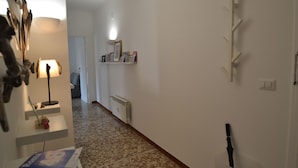 Un passadís amb un radiador, una estant amb quadres emmarcados i un penjador.