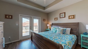Une chambre avec un grand lit, une commode, une table de chevet et une vue sur l’extérieur.