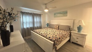 A bedroom with a bed, nightstands, a ceiling fan, a window with curtains, and a painting on the wall. - Paradise awaits! (Sarasota)