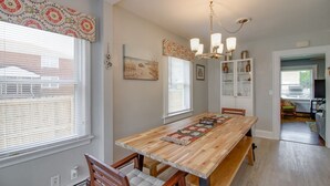 A dining area with a wooden table, chairs, a chandelier, and a cabinet with glass doors. - Willoughby 4BR Coastal Home • Steps to Shore (Norfolk)