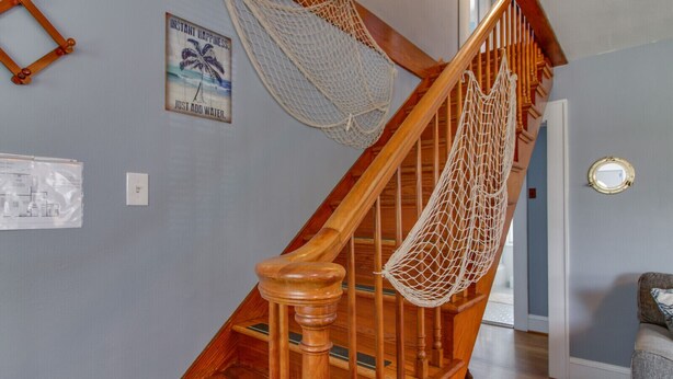 A wooden staircase with a net hammock hanging from the handrail. - Willoughby 4BR Coastal Home • Steps to Shore (Norfolk)