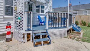 A house with a covered porch, a small deck, and a fenced area with blue chairs. - Willoughby 4BR Coastal Home • Steps to Shore (Norfolk)