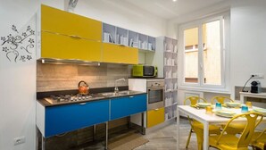 Una cocina moderna con armarios azules y amarillos, un microondas y un comedor con sillas amarillas.