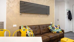 Una sala de estar moderna con un sofá de cuero marrón, almohadones estampados y un radiador fijado a la pared.