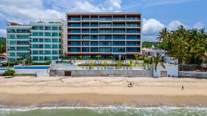 A beachfront hotel with multiple floors, a swimming pool, and palm trees. - Luxury 4 bed/4 bath Beach Front Condo - Bucerias (Bucerías)