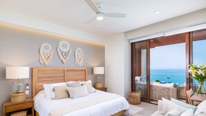 A bedroom with a large bed, two bedside tables, a ceiling fan, and a view of the ocean through a sliding glass door. - Luxury 4 bed/4 bath Beach Front Condo - Bucerias (Bucerías)