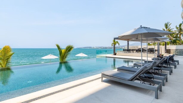 A poolside area with lounge chairs and umbrellas, overlooking the sea. - Luxury 4 bed/4 bath Beach Front Condo - Bucerias (Bucerías)