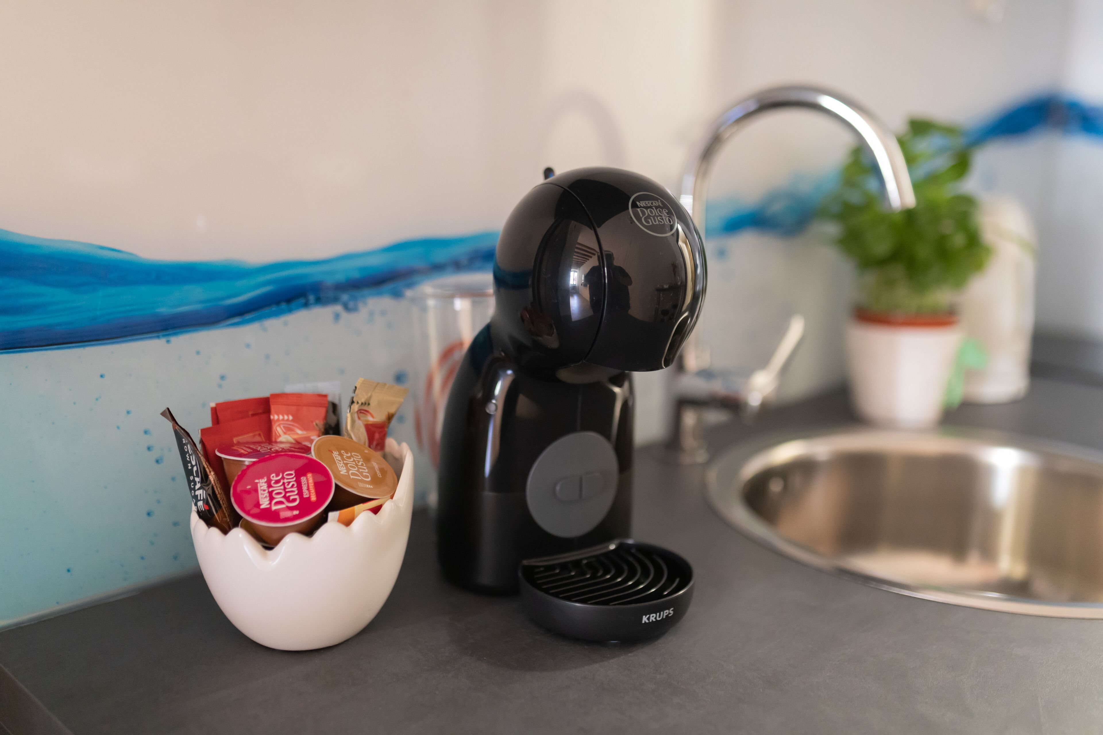 A kitchen with a coffee maker, a bowl of snacks, and a sink.