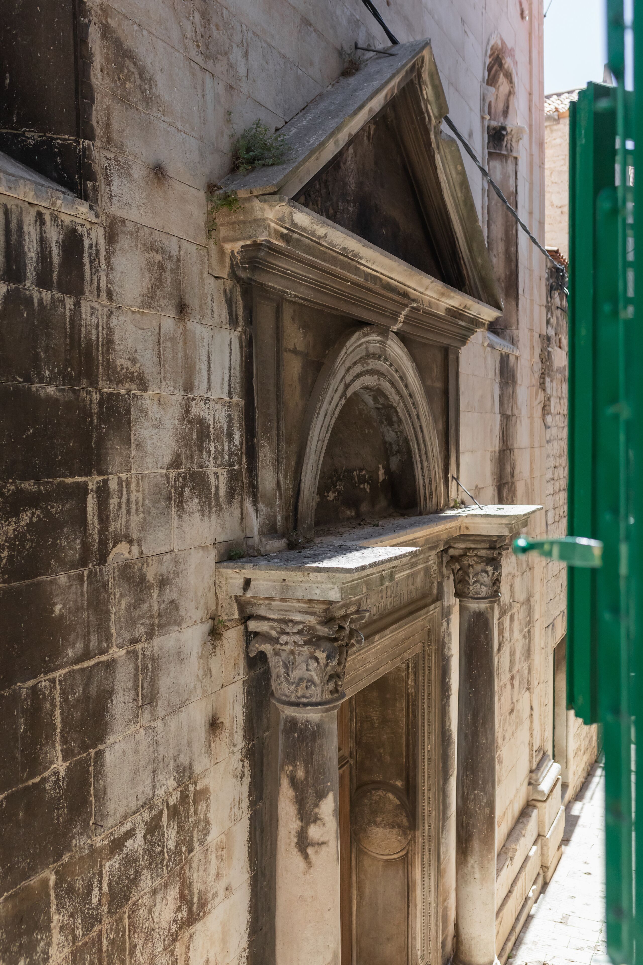 La façade d’un bâtiment historique, ornée d’une arche en pierre et de colonnes.