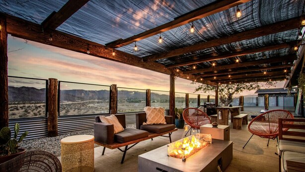 Un patio exterior con mobiliario, una chimenea y vistas a las montañas.