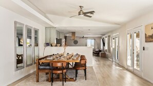 Un comedor amplio con una larga mesa de madera, varias sillas y un jarrón central.