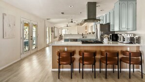 Una cocina moderna con una isla central, taburetes de bar y armarios azul claro.