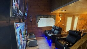 A cozy room with a wooden interior, a sofa, a TV, and a massage table.