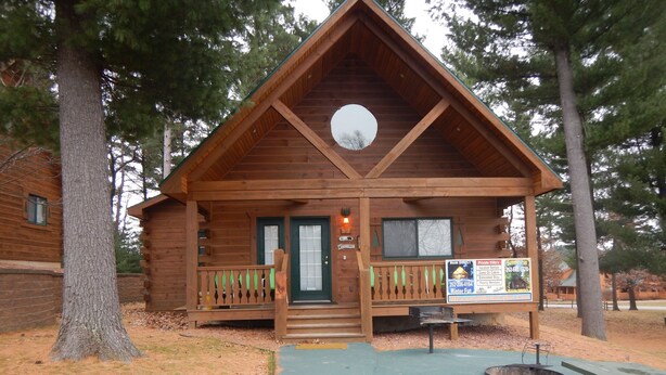 A wooden cabin with a porch, a circular skylight, and a signboard.