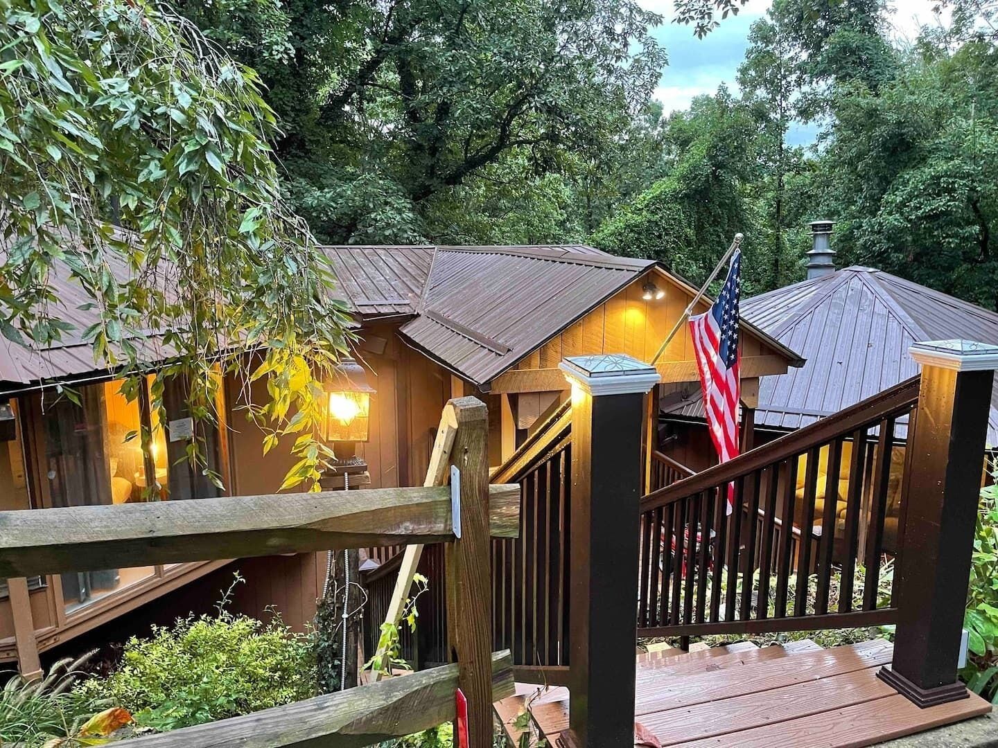 A wooden cabin with a porch and a staircase leading to a deck.