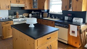 Een keuken met houten kastjes, een fornuis, magnetron, gootsteen en broodrooster.