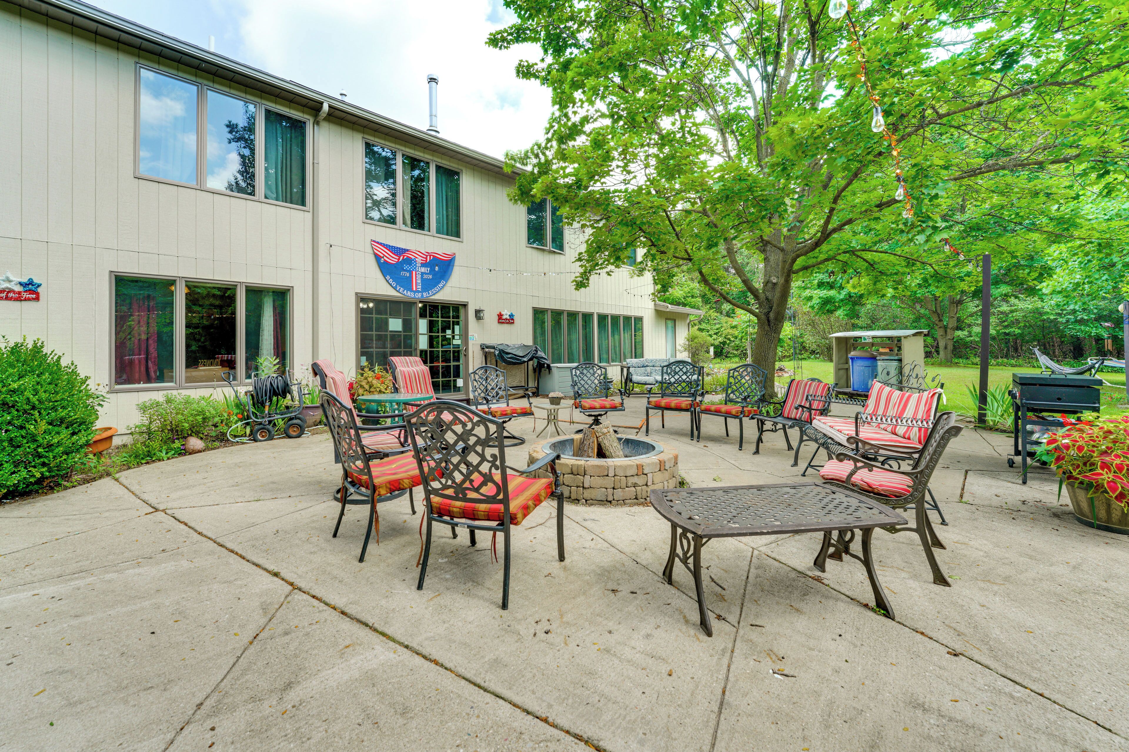 Un espace extérieur aménagé en terrasse, avec plusieurs coins salon, un foyer et un bâtiment orné des armoiries de la famille.