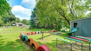 A playground with tire swings and a slide, surrounded by trees and a small building. - Southeast Michigan Escape w/ Outdoor Fun (Adrian)
