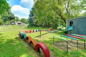 A playground with tire swings and a slide, surrounded by trees and a small building. - Southeast Michigan Escape w/ Outdoor Fun (Adrian)