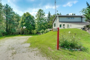 A house with a sign reading 'GUESTS' in front, surrounded by greenery and a gravel path. - Southeast Michigan Escape w/ Outdoor Fun (Adrian)