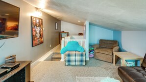A compact living space with a couch, a small table, a television, and a poster on the wall. - Southeast Michigan Escape w/ Outdoor Fun (Adrian)