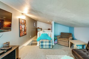 A compact living space with a couch, a small table, a television, and a poster on the wall. - Southeast Michigan Escape w/ Outdoor Fun (Adrian)