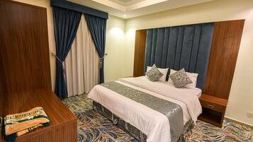 A hotel room with a large bed, a wooden wardrobe, and a patterned carpet.