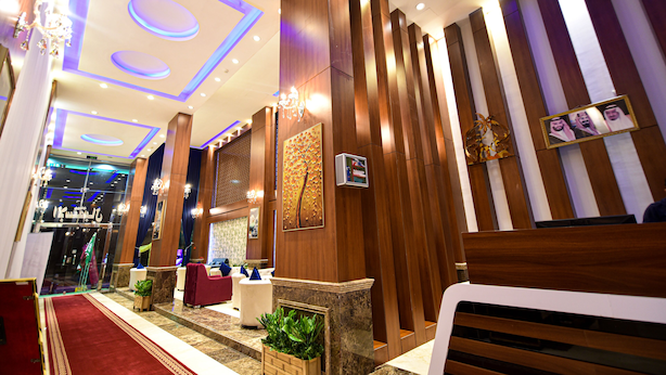 Un hall de hotel con alfombra roja, paneles de madera y una recepción.