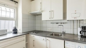 Una cucina moderna con mobili bianchi, lavastoviglie integrata, lavello in acciaio inossidabile e macchina da caffè.