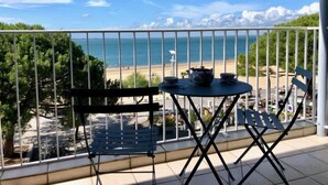 Un balcone con tavolo e sedie affacciato su una spiaggia.