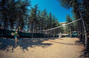 An outdoor volleyball court surrounded by trees.
