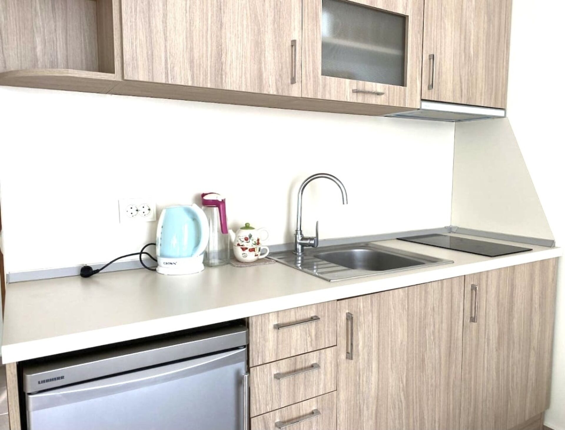 A kitchen with a dishwasher, a sink, and a kettle.